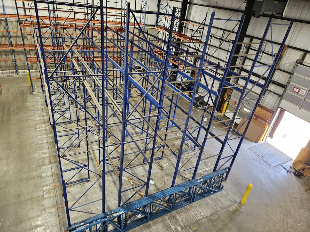 Rows of tall structural pallet rack frames during teardown and reinstallation in a beverage warehouse